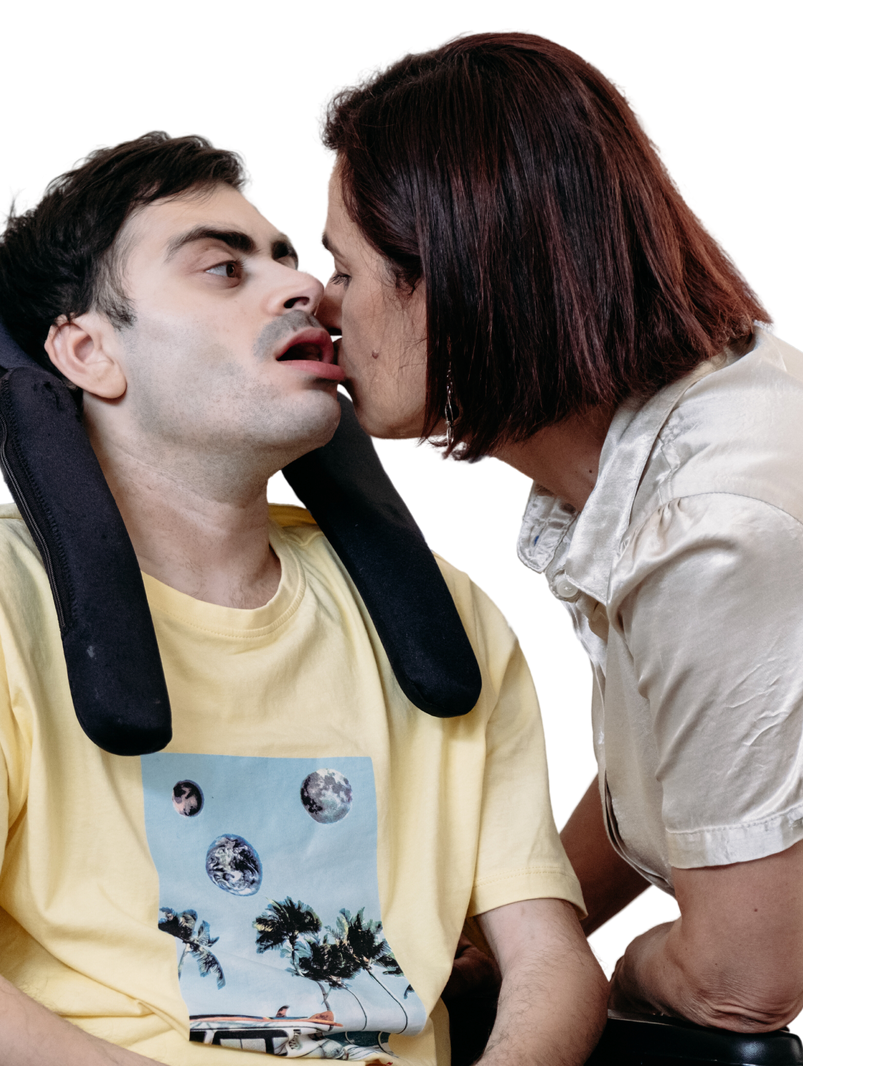 Simone, un utente adulto della Lega del Filo d'Oro ritratto mentre riceve un bacio dalla sua mamma. La foto li ritrae in primo piano. 