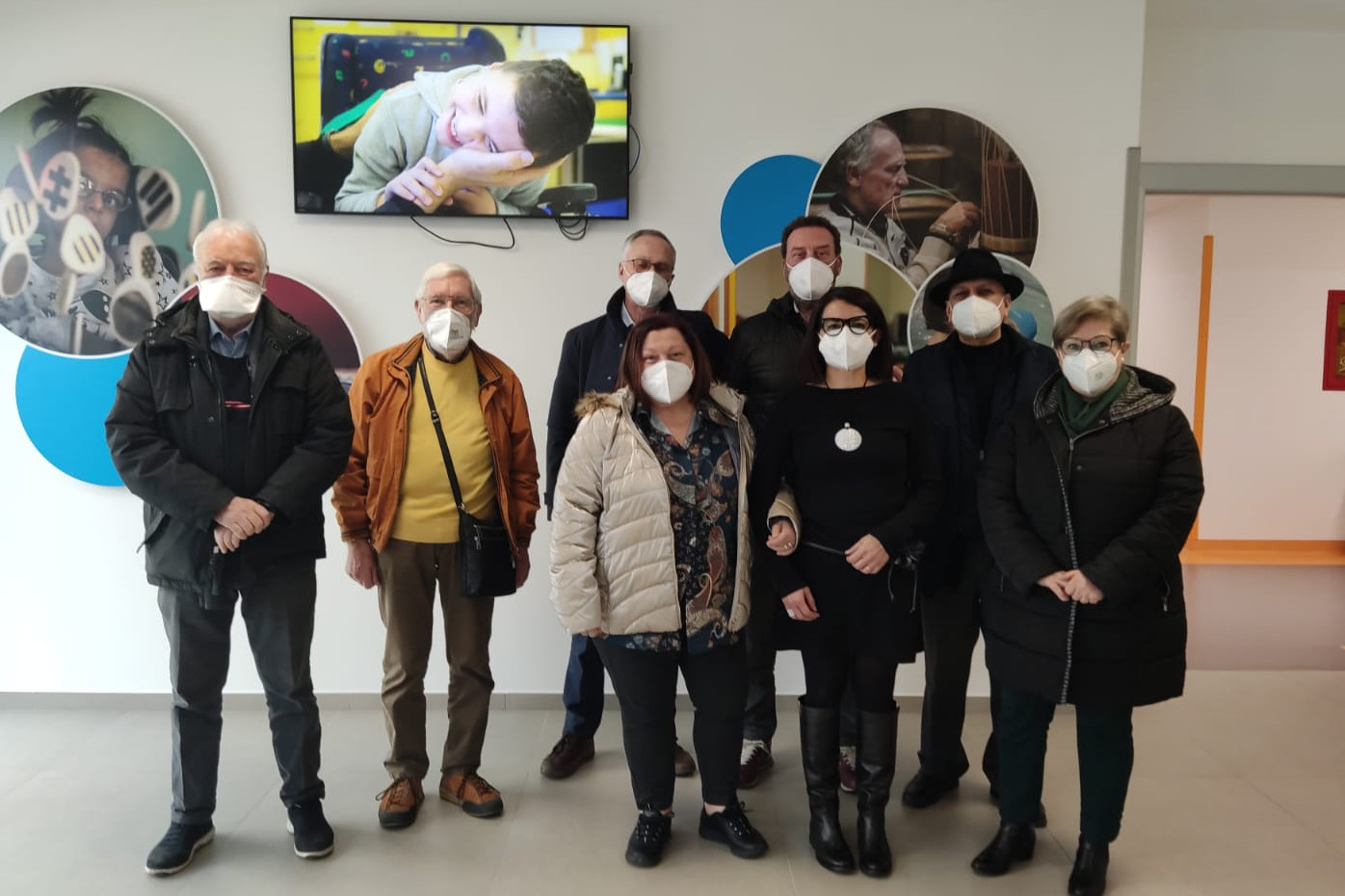 Un gruppo composto dai rappresentanti del Comitato dei familiari con mascherina ffp2 posa in piedi nell'altrio del Centro di Osimo.