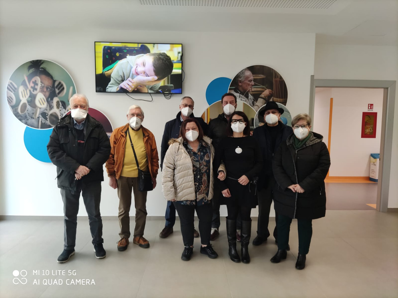 Un gruppo composto dai rappresentanti del Comitato dei familiari con mascherina ffp2 posa in piedi nell'altrio del Centro di Osimo. 