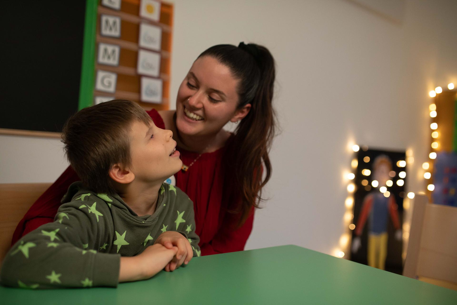 Matteo, bambino cieco, accanto alla sua educatrice. Entrambi sorridenti, in un’atmosfera di amore e calore umano che racconta affetto e relazione autentica.
