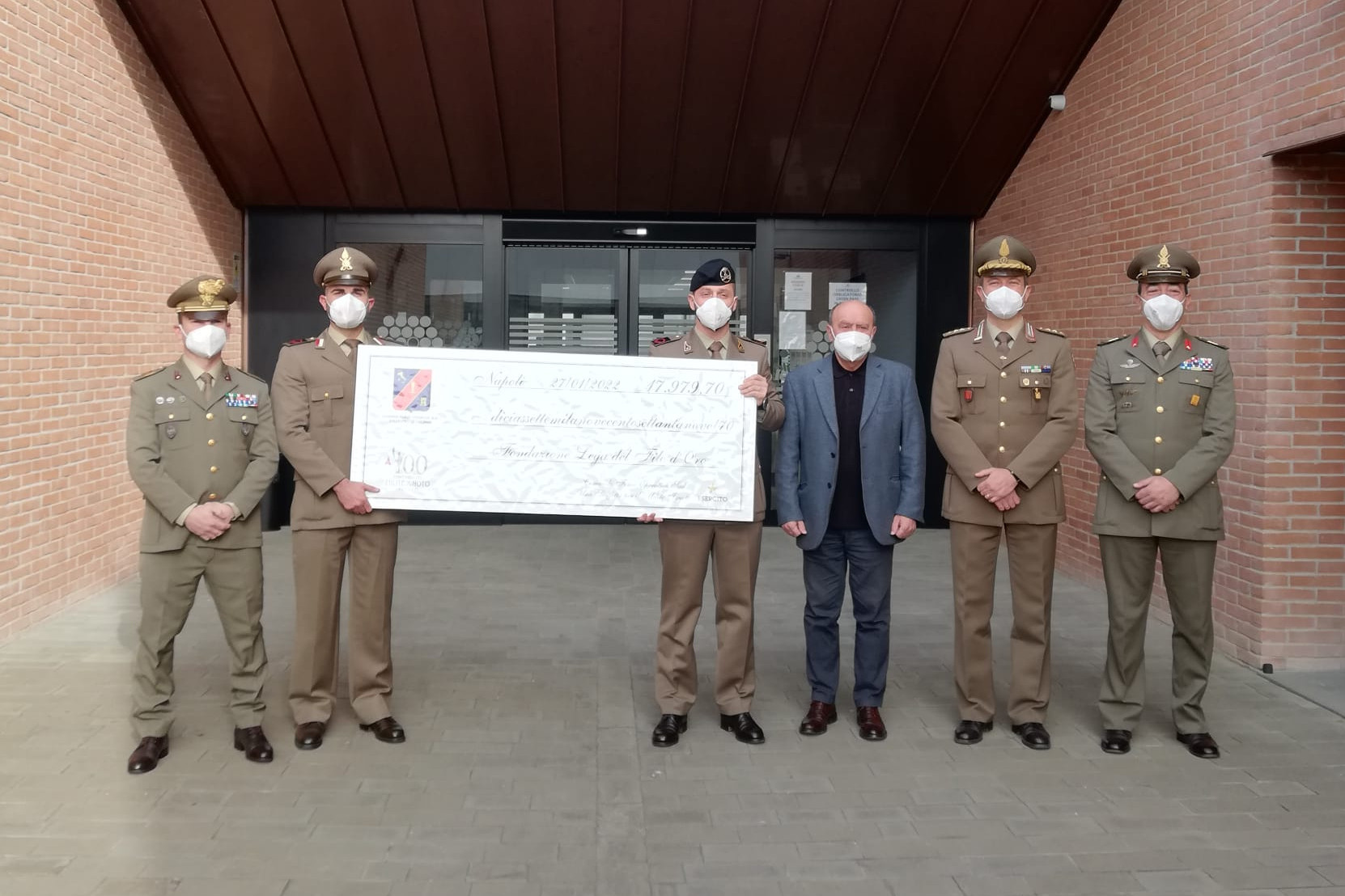 Nella foto ci sono 5 militari, insieme a Rossano Bartoli Presidente della lega del filo d'oro, che reggono un assegno di beneficenza.