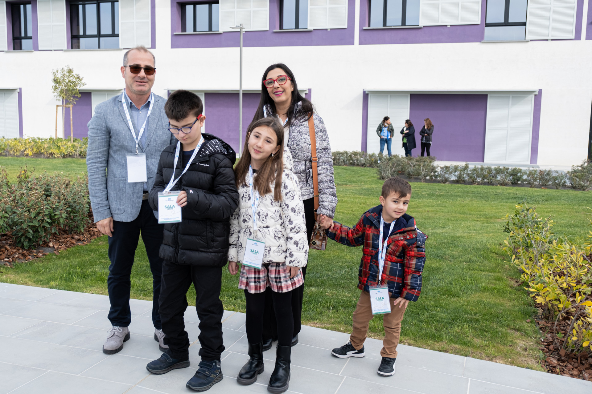 Biagio Luigi, bambino utente della Lega del Filo d’Oro, è ritratto insieme ai suoi genitori e fratellini. Si trovano nel piazzale esterno del Centro Nazionale di Osimo.