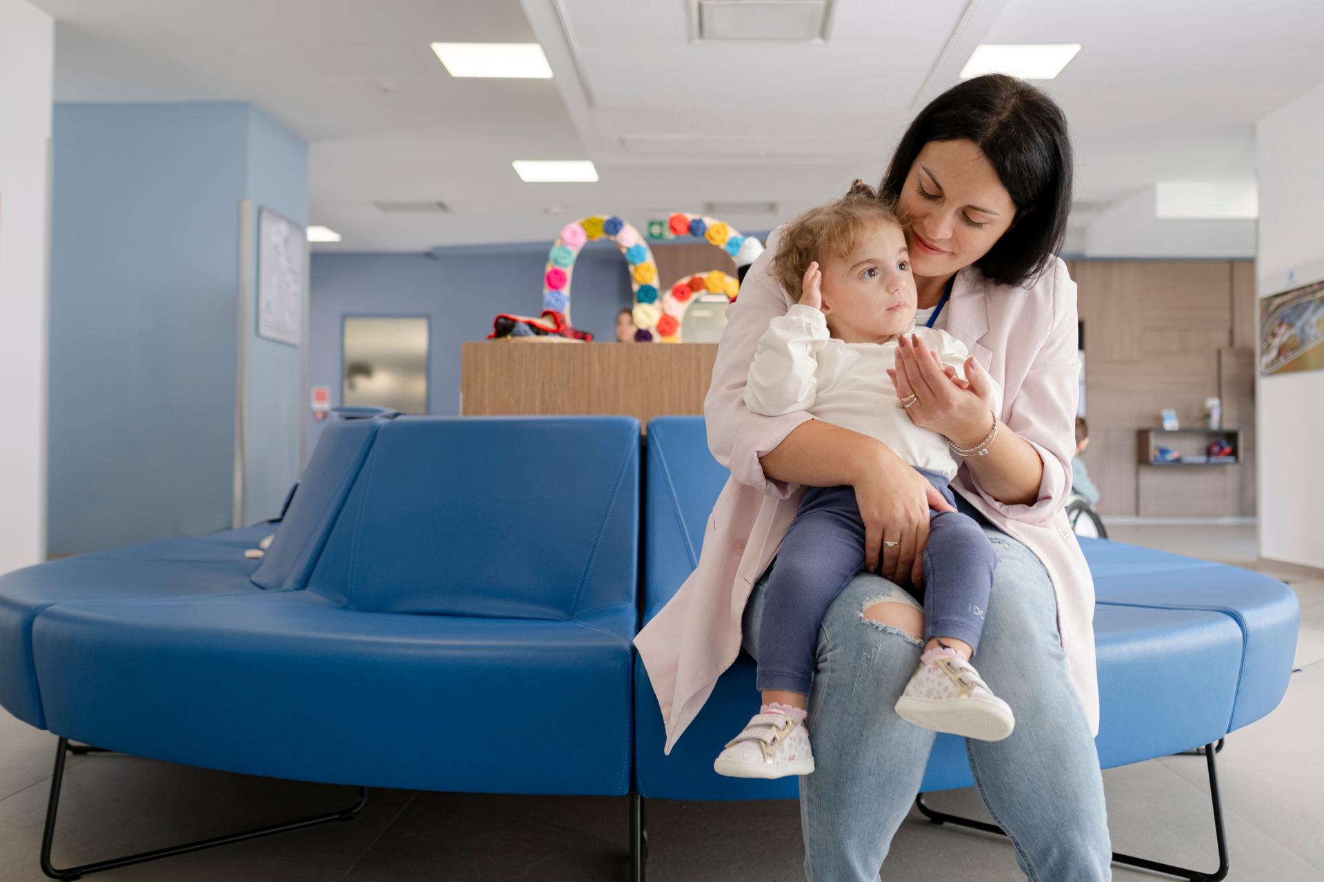 La piccola Benedetta, in braccio a sua mamma Agostina, in un bellissimo abbraccio d'amore sedute nel divanetto dell'ingresso del Centro Nazionale a Osimo