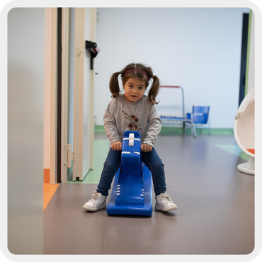 La piccola Letizia sul cavallo a dondolo gioca nelle stanze della Lega del Filo d'Oro.