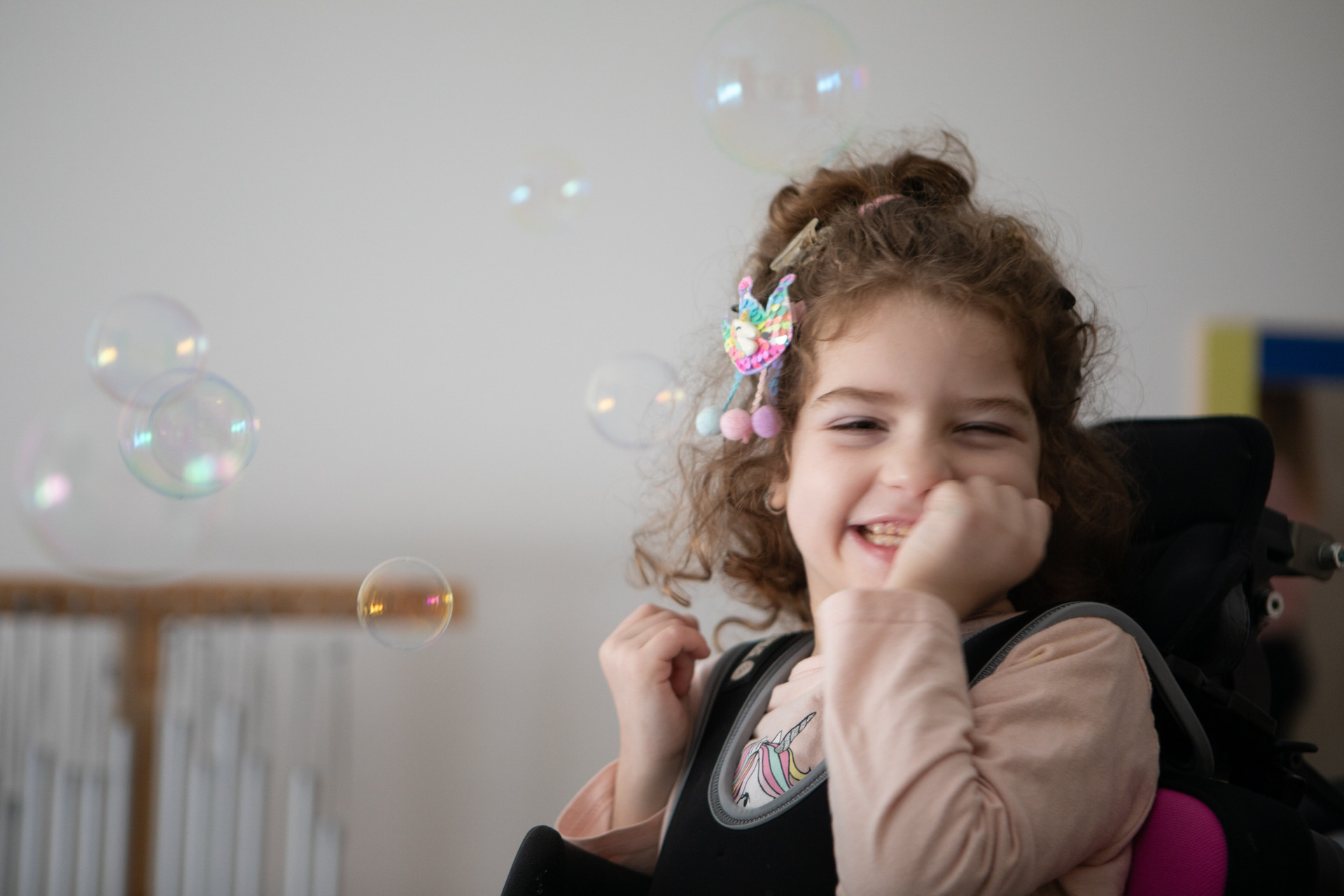 Melissa sorride mentre gioca con le bolle di sapone che volano 