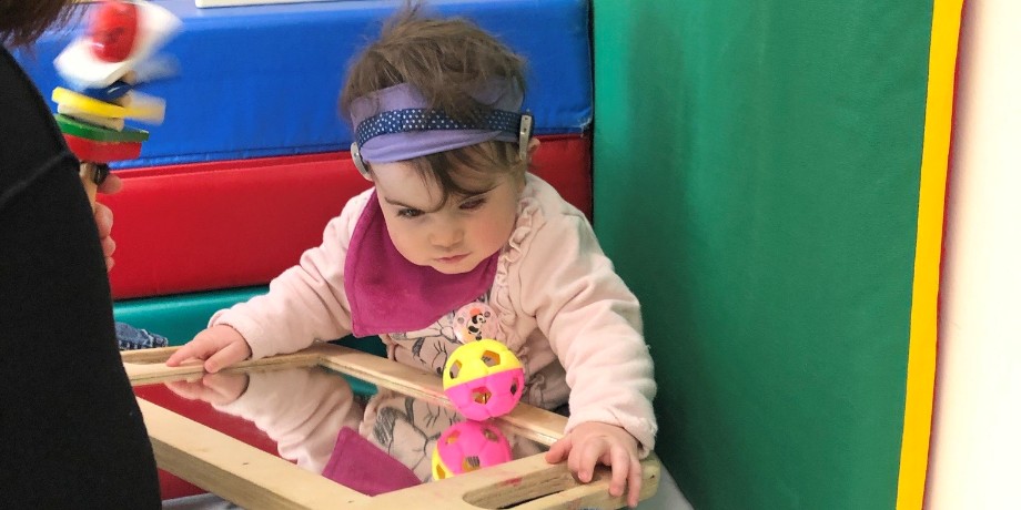 La piccola Letizia, bambina con la sindrome di Charge, qui aveva più di un anno circa mentre è a trattamento del Diagnostico. Tiene sulle gambe uno specchio