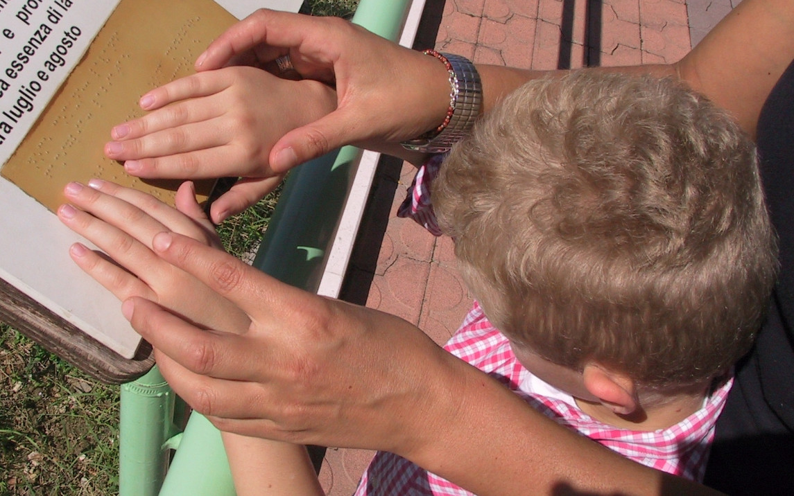 Un bambino sordocieco, che legge una scritta in Braille