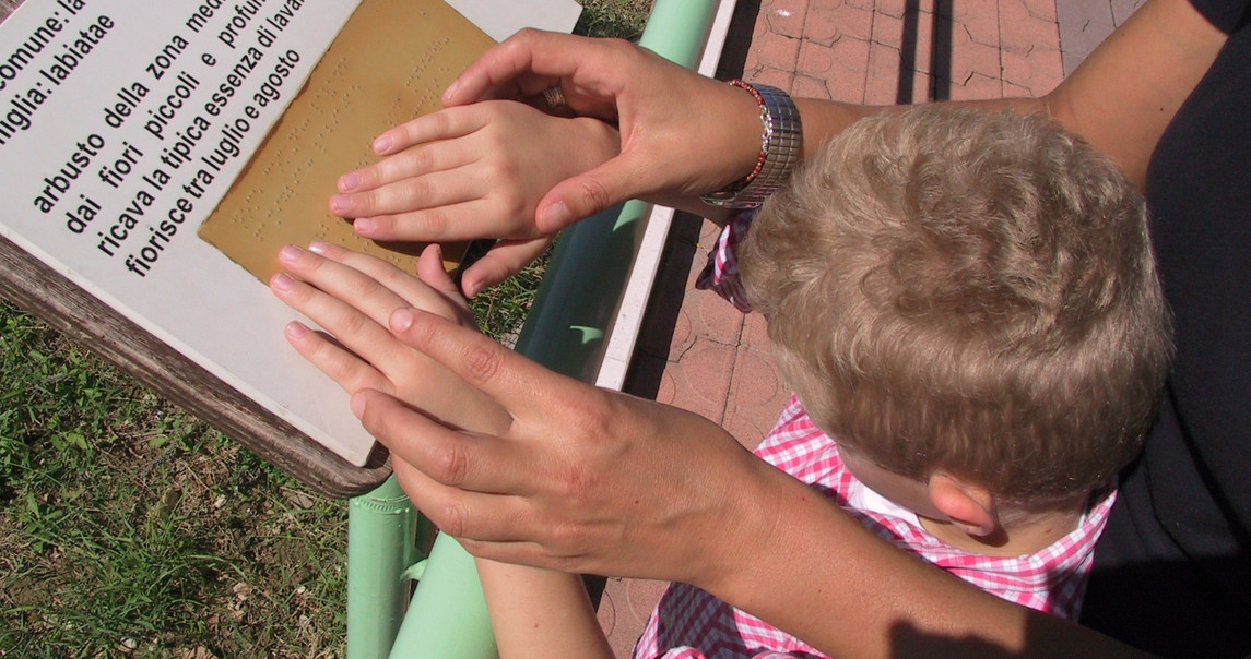 Un bambino sordocieco, che legge una scritta in Braille