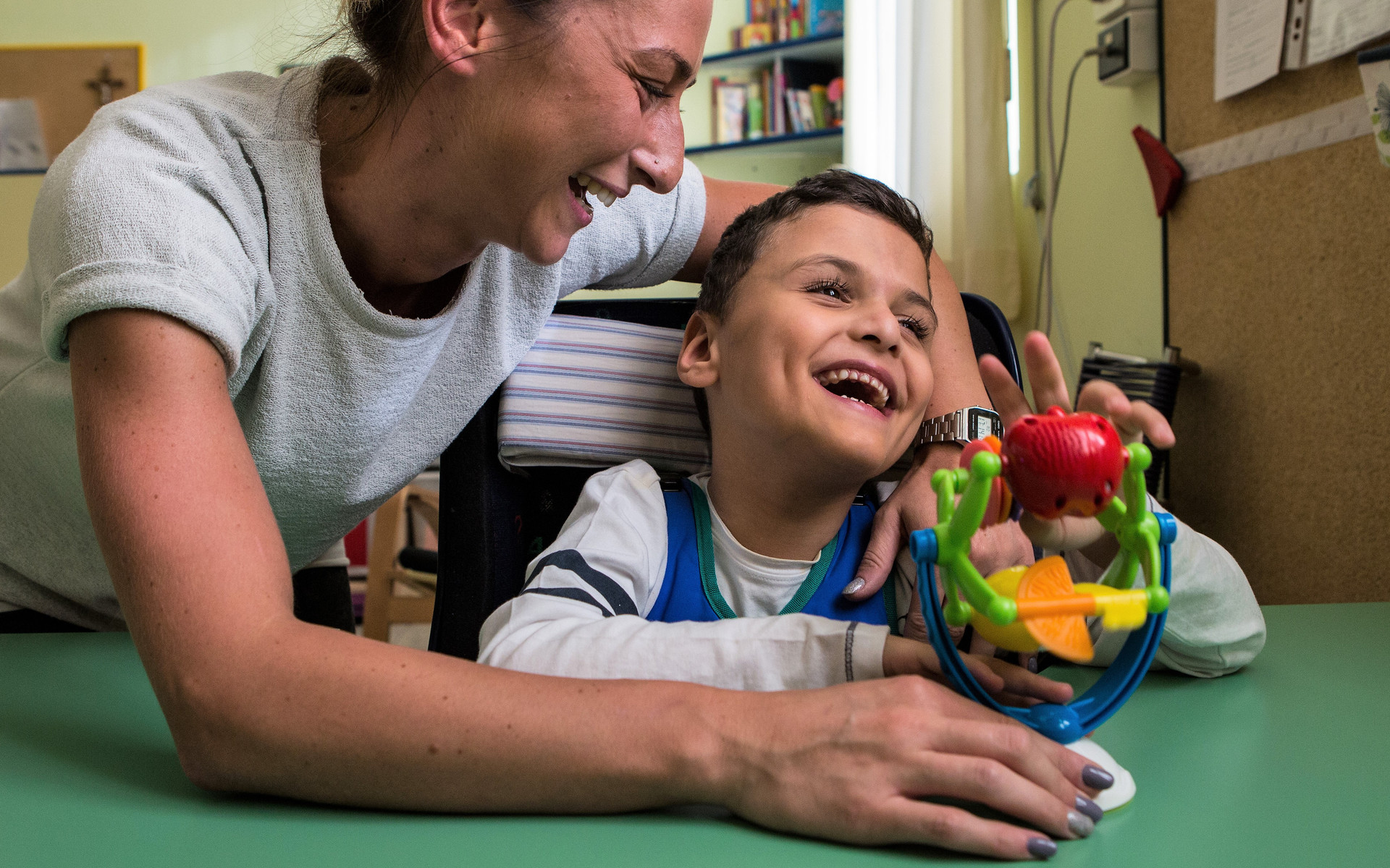 Francesco, piccolo utente del Centro di Osimo, ride con la sua educatrice mentre usano un giocattolo con stimolazioni sensoriali