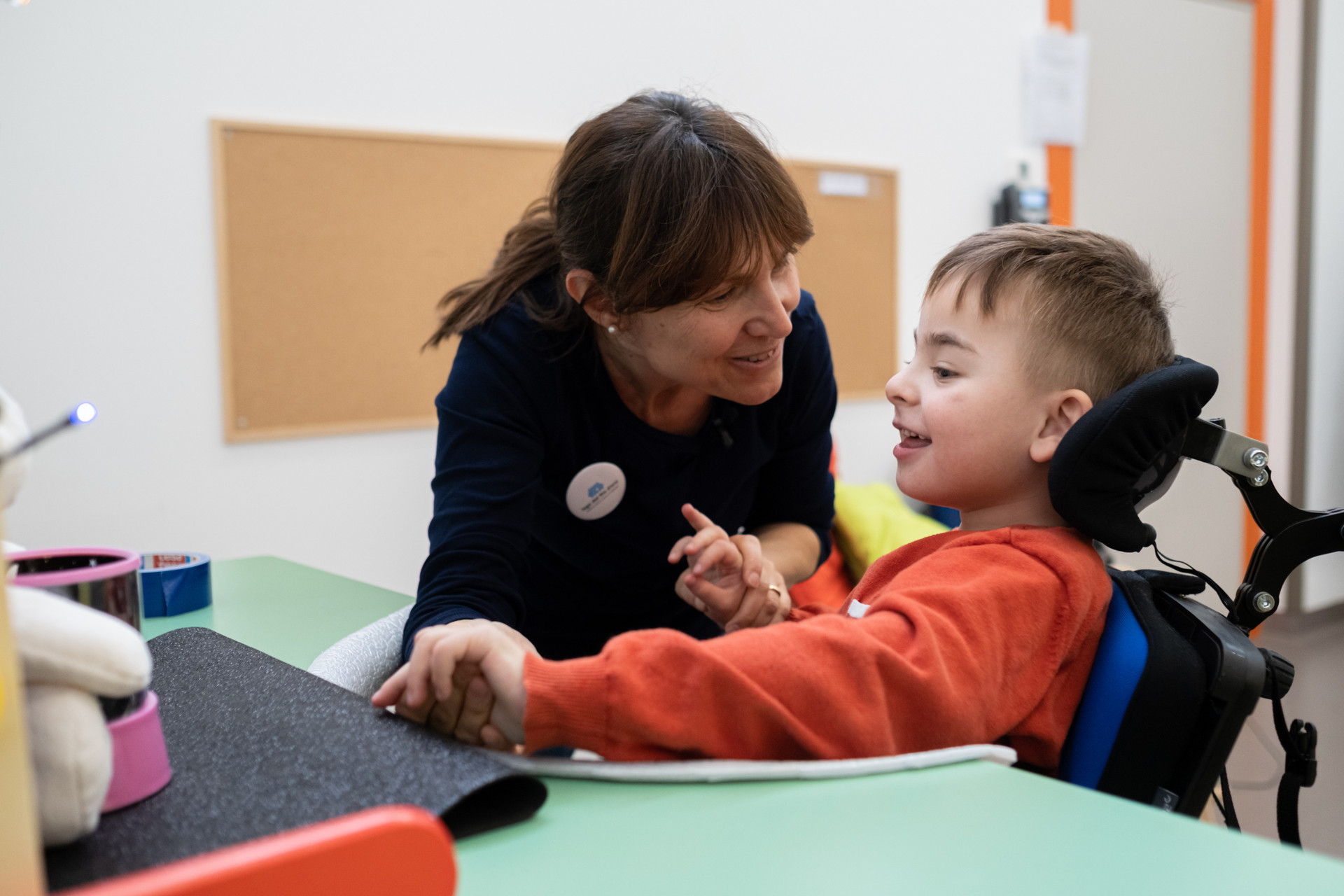 Edoardo, bambino della Lega del Filo d’Oro, è ritratto insieme a una donna che potrebbe essere la sua mamma o un’operatrice.