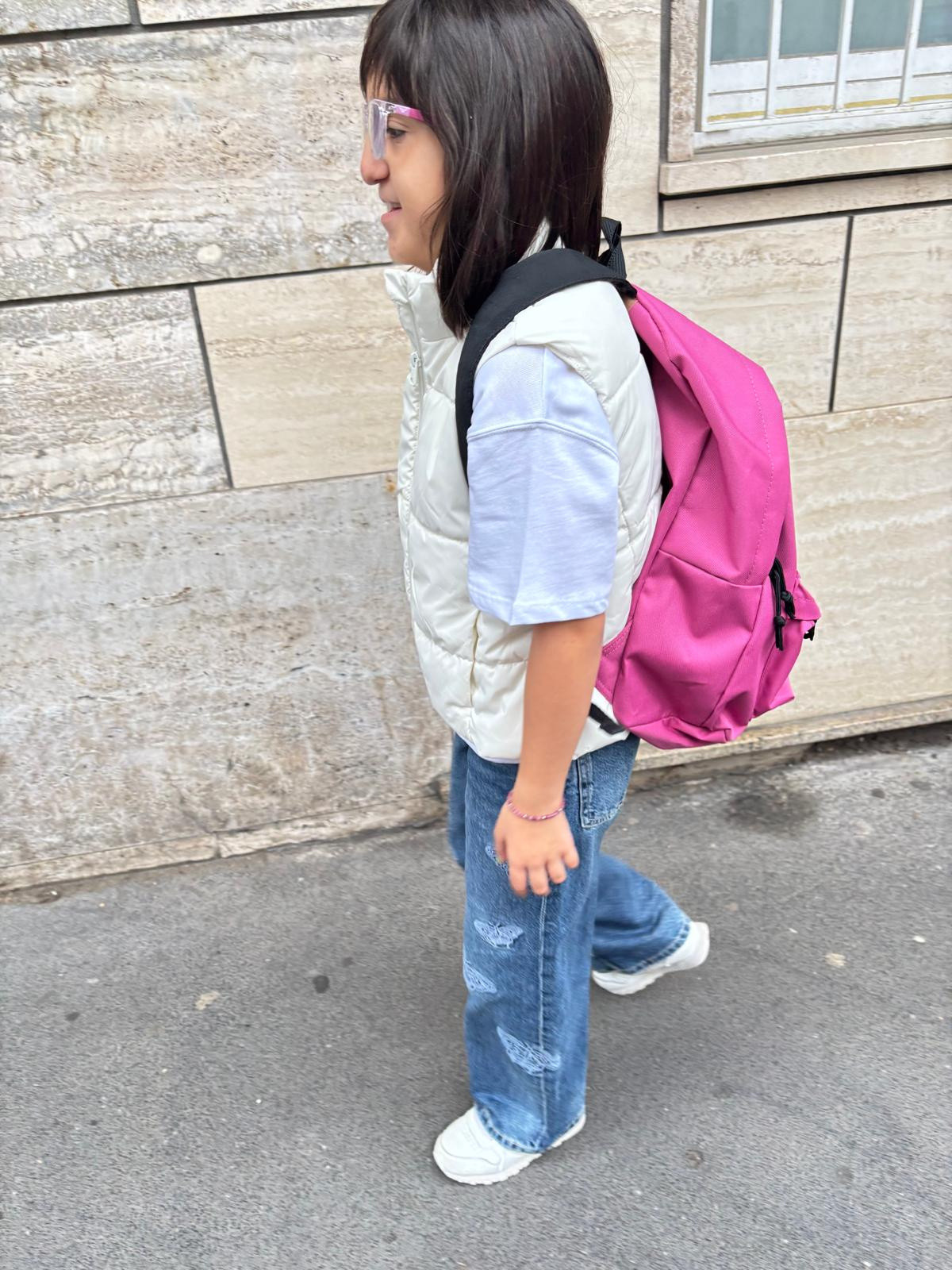 Giulia, con il suo zainetto fucsia, percorre il marciapiede in direzione scuola. Primo giorno dell'anno scolastico 2025/26.
