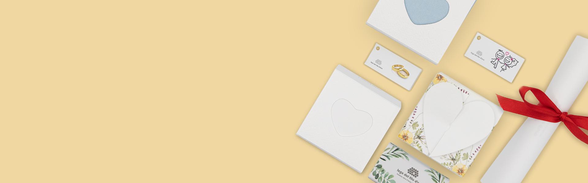 Composizione di prodotti su sfondo giallo, con bomboniera a cuore, pergamena, biglietto di nozze e biglietto evergreen, perfetti per celebrare occasioni speciali con eleganza e stile.