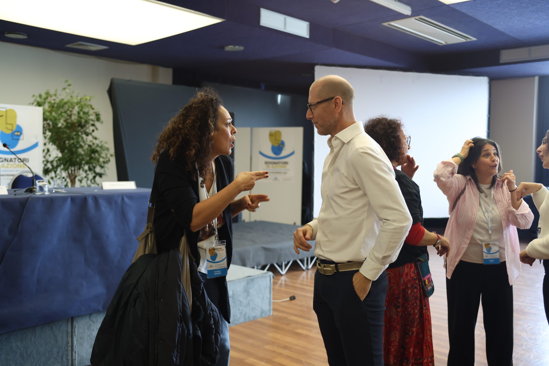 Durante le testimonianze al Forum dei Volontari, alcune persone dialogano tra loro utilizzando la LIS (Lingua dei Segni Italiana). Uno scatto spontaneo che racconta inclusione, comunicazione accessibile e partecipazione.