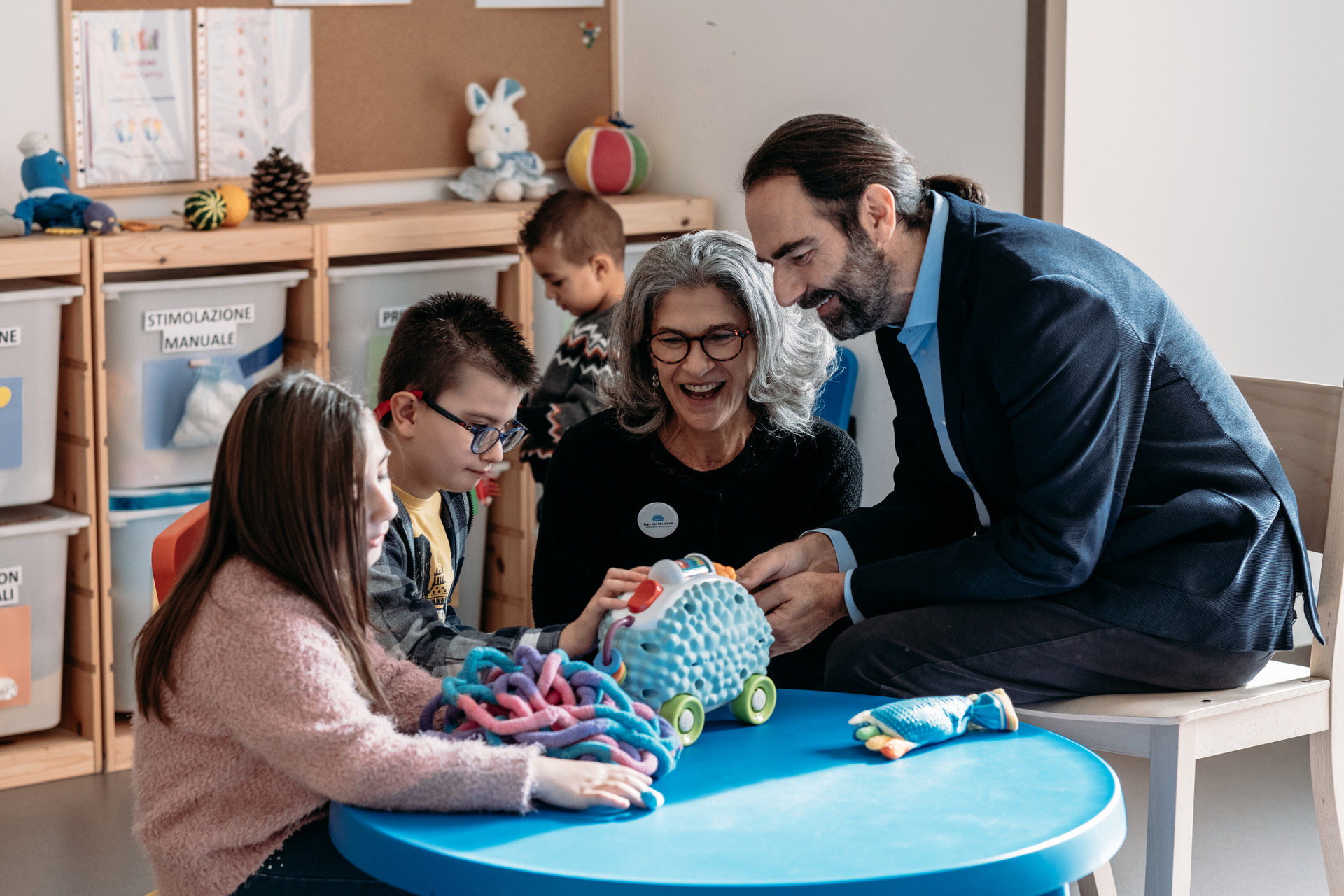 Neri Marcorè, testimonial della Lega del Filo d'Oro, insieme a Luigi, i suoi fratellini e l'educatrice giocano tutti insieme mentre sono sul set dello shooting di campagna del 5x1000