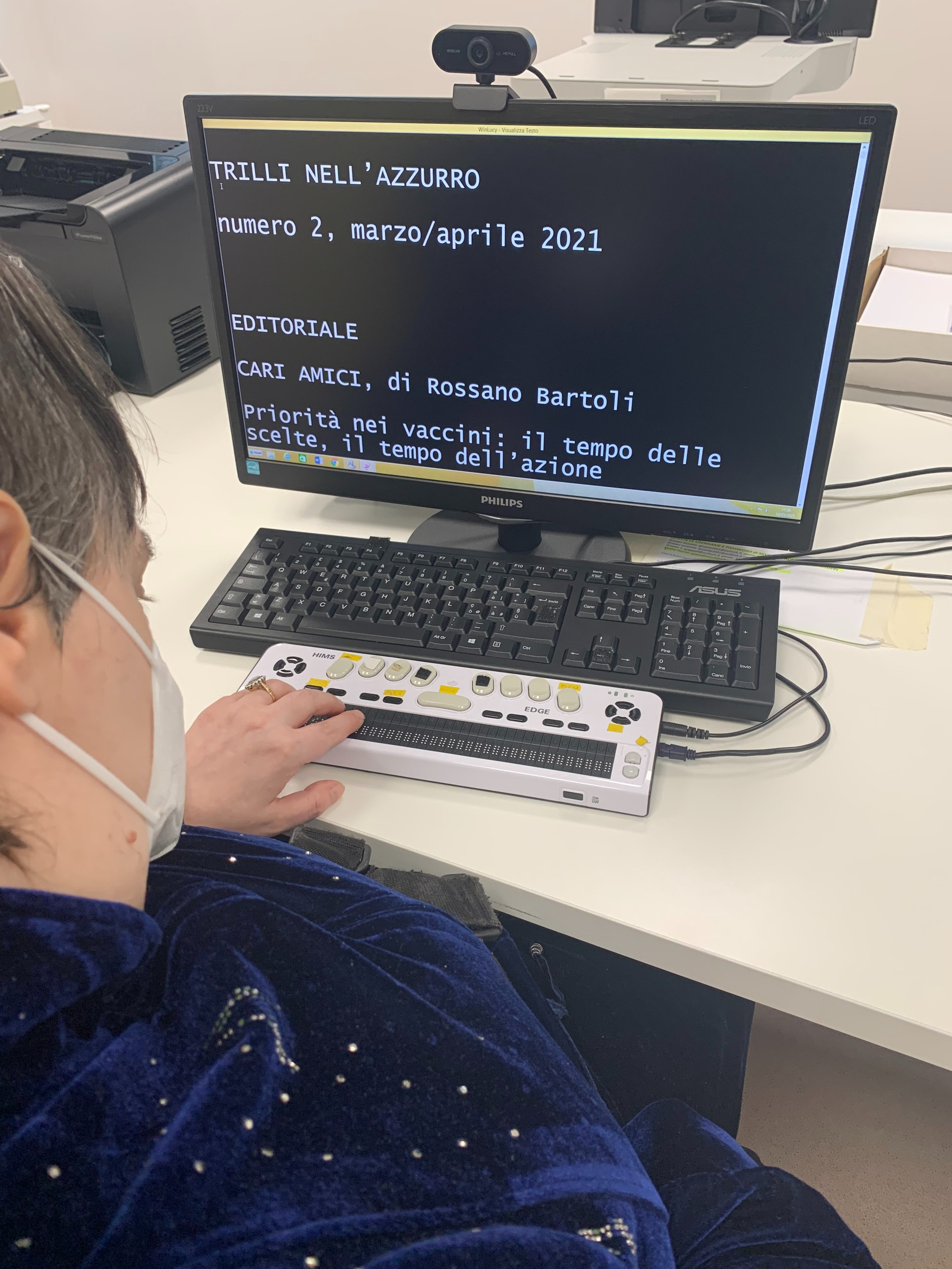 Un utente siede ad un tavolo e utilizza un computer e un altro strumento per accedere alla piattaforma Win Lucy, di cui vediamo alcune scritte sulle schermo. 