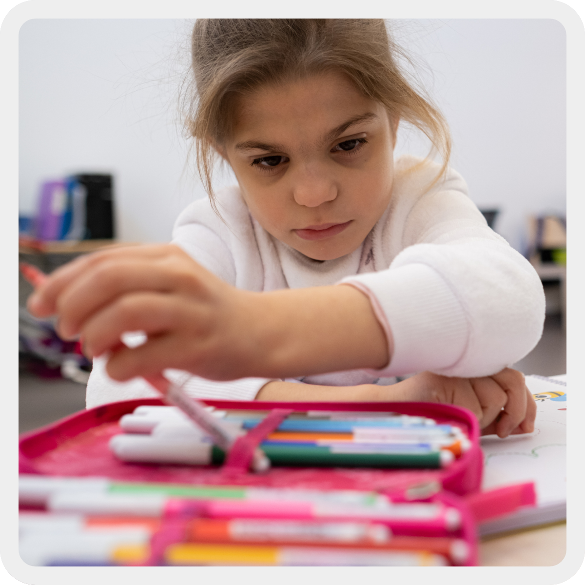 Sveva, bambina di circa 10 anni con la Sindrome di Charge, prende un pennarello rosa dal suo astuccio fucsia mentre fa attività di pre grafismo al centro Nazionale. 