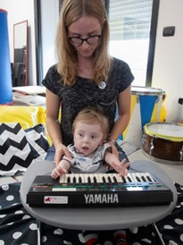 Il piccolo Gabriele, ospite del Centro Diagnostico, svolge un'attività educativo-riabilitativa con l'aiuto di una pianola che il bimbo suona sorretto dalla sua educatrice