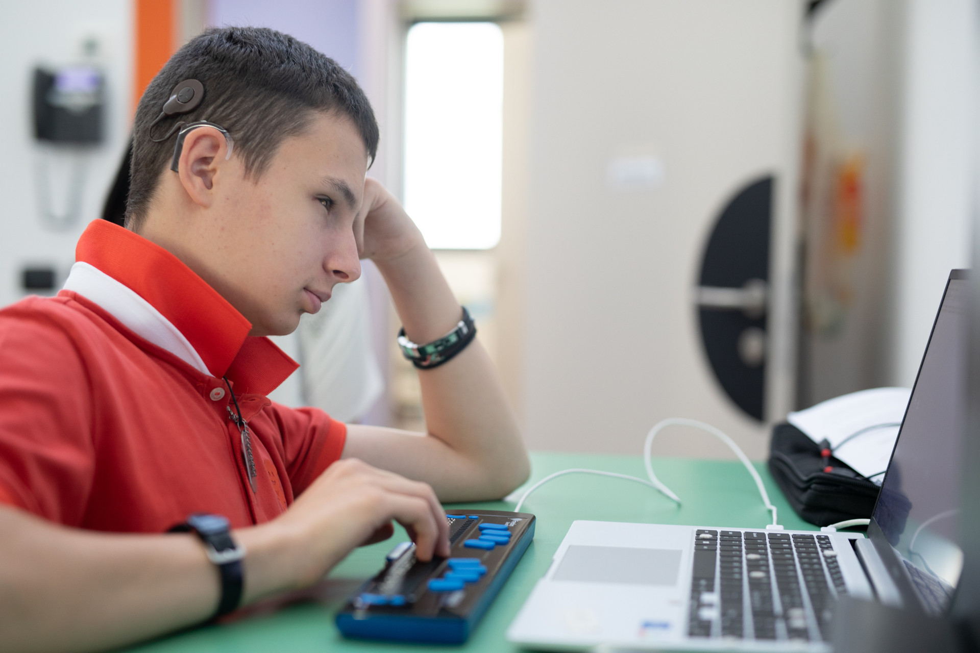 Massimo, giovane utente della Lega del Filo d'Oro, utilizza una barra braille collegata a un computer per scrivere in autonomia.
