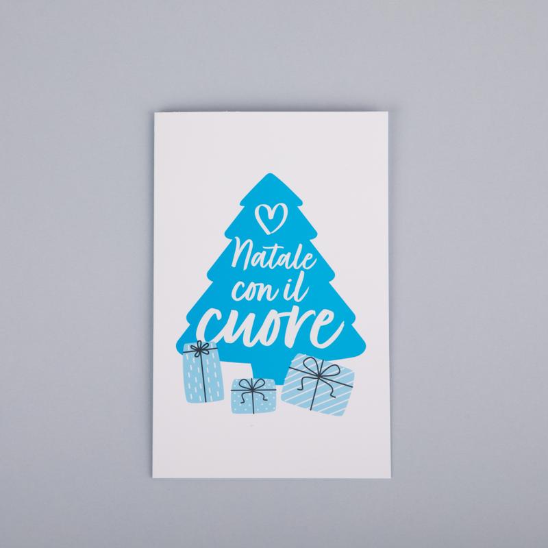 Biglietto di auguri con disegnata la sagoma di un grande albero di Natale azzurro con la scritta "Natale con il cuore" e 3 pacchetti regalo