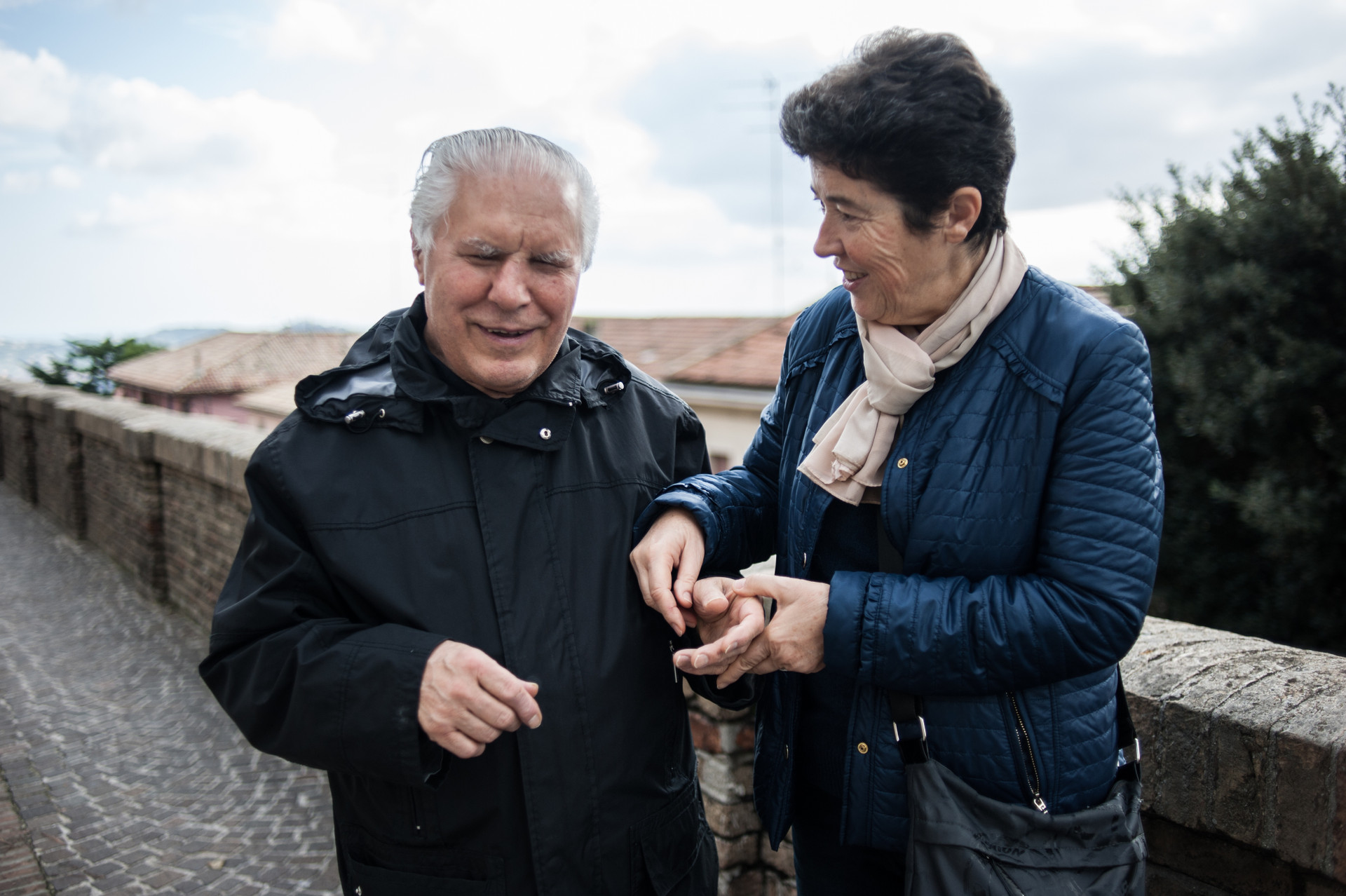 Angelo, utente anziano del Centro di Osimo, sorridente al fianco della sua interprete 