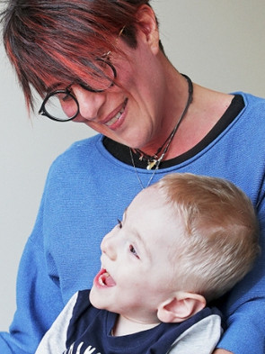 Il piccolo Gabriele, un bambino utente della Lega del Filo d'Oro, ride in braccio alla sua educatrice