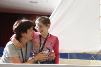 Una volontaria abbraccia una piccola utente, entrambe si guardano ridendo divertite