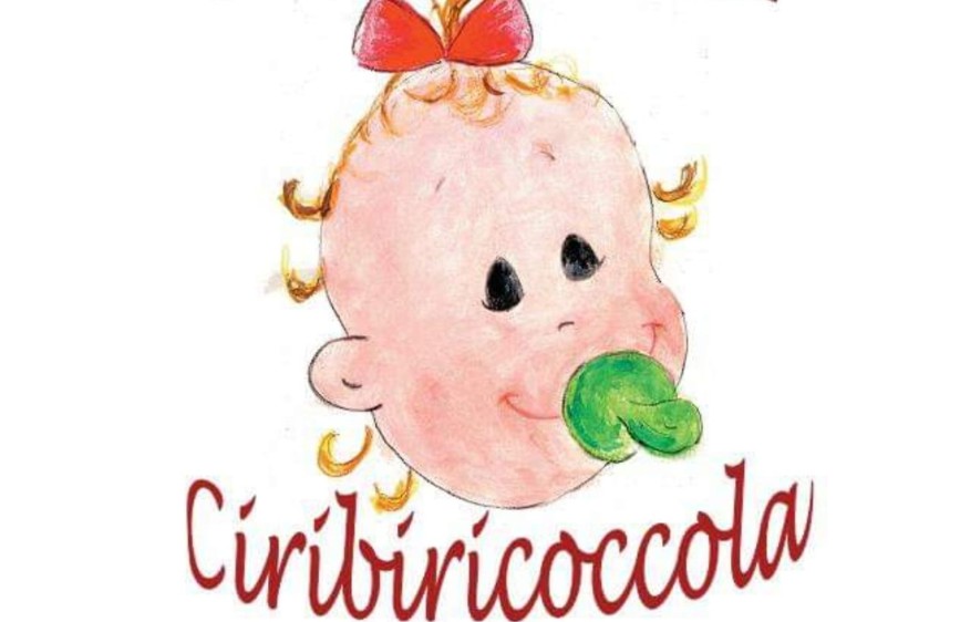 L'immagine è un disegno di un dolce viso di bambino con riccioli dorati e un grande fiocco rosso sulla testa, che indossa un ciuccio verde. Sotto il disegno, in un carattere corsivo rosso, si legge la parola "Ciribiricoccola".