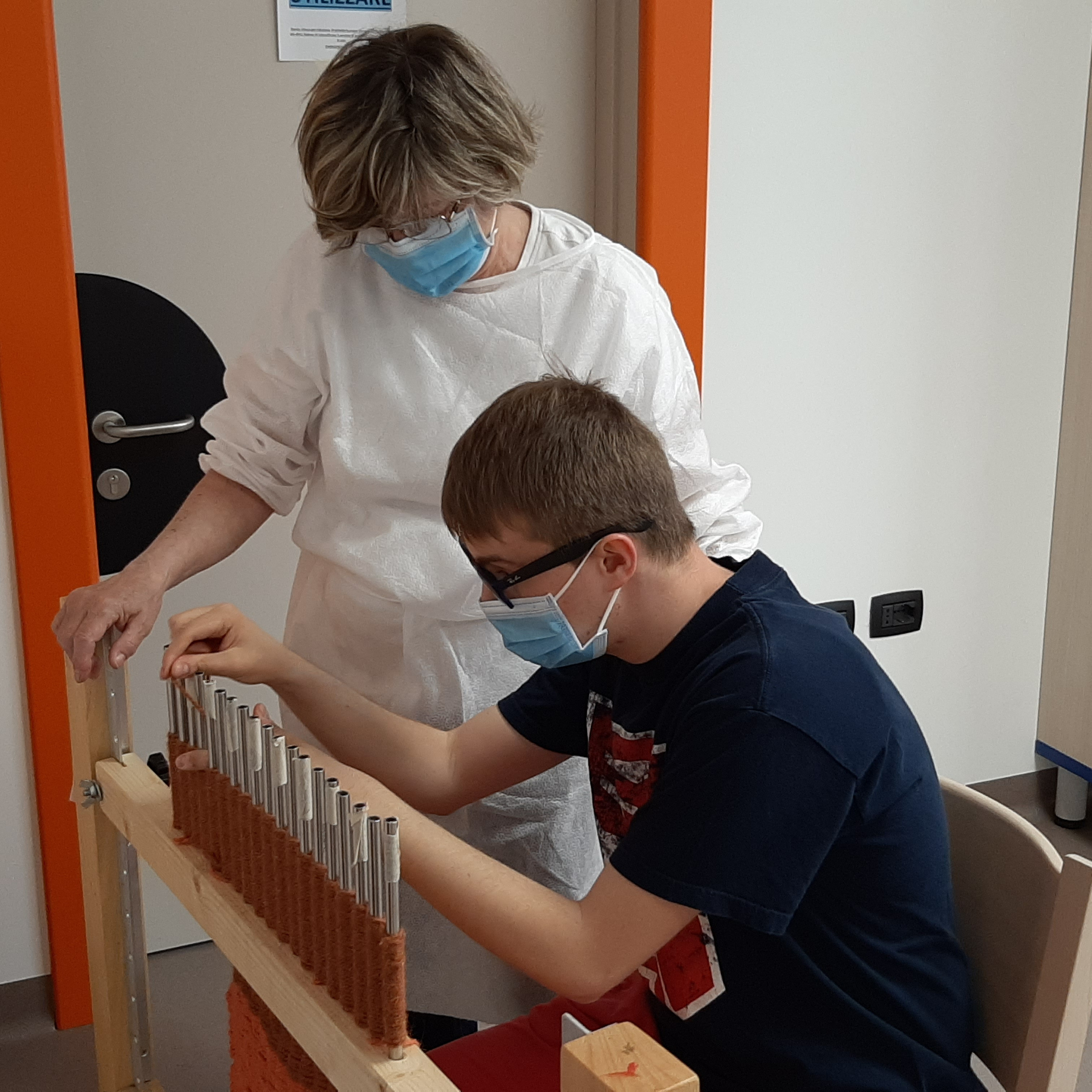 Un utente e un'educatrice nel laboratorio di filato con DPI anti covid