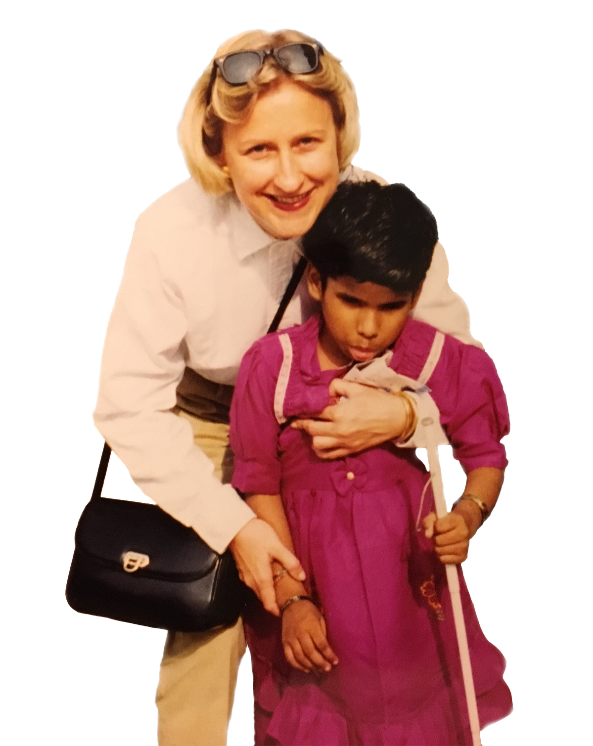 Foto scontornata di Anna che abbraccia sorridendo sua figlia Rekha. La bambina (circa 7 anni nella foto, utente Lega del Filo d'Oro) tiene in mano un bastone bianco per non vedenti