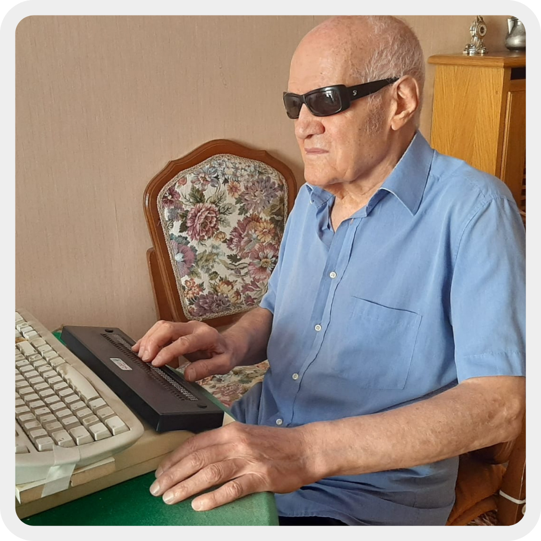 Amerigo, persona sordocieca, mentre usa la barra braille per scrivere al computer.