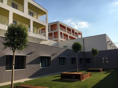 Foto degli edifici 3 e 4 del primo lotto del Centro Nazionale. La foto è scattada da uno dei giardini interni dell'edificio 1, con alberi e panchine 