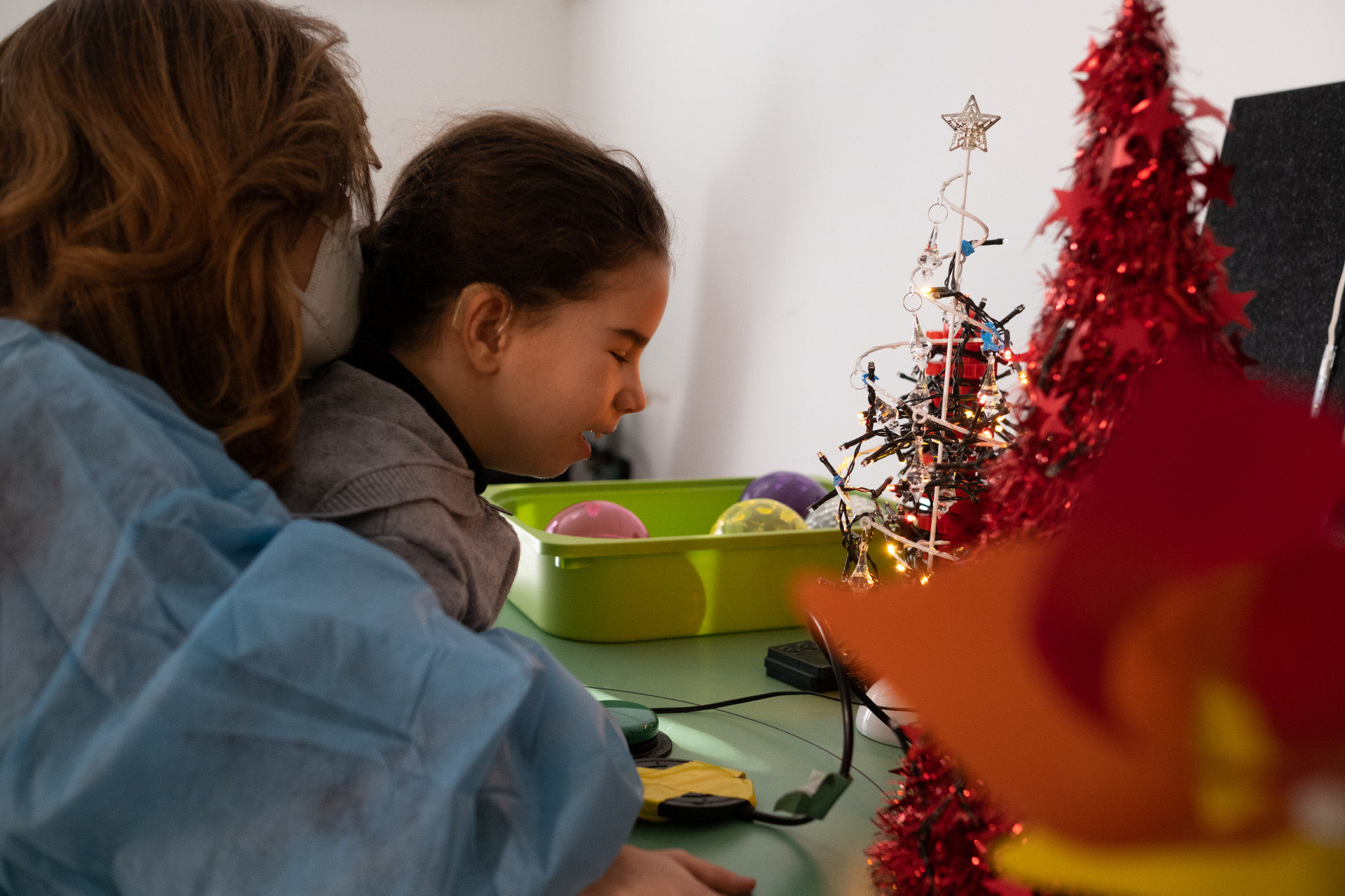 Giulia, piccola utente della Lega, accende le lucine dell'Albero di Natale insieme alla sua educatrice