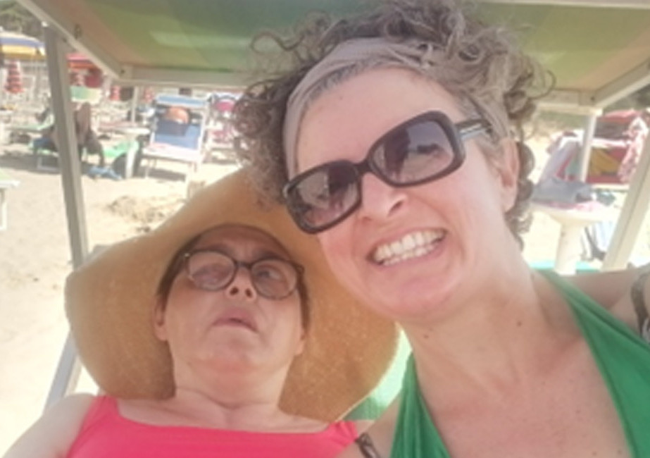 Anna, volontaria del Centro della Lega del Filo d'Oro di Modena, insieme ad un utente al mare