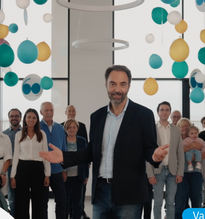 Foto che ritrae Neri Marcorè tra i palloncini, durante le riprese dello spot di Campagna del 60° anniversario della Lega del Filo d'Oro, nella mensa del Centro Nazionale di Osimo. Sullo sfondo molte persone che insieme sostengono la Fondazione, famiglie, utenti, personale specializzato, sostenitori