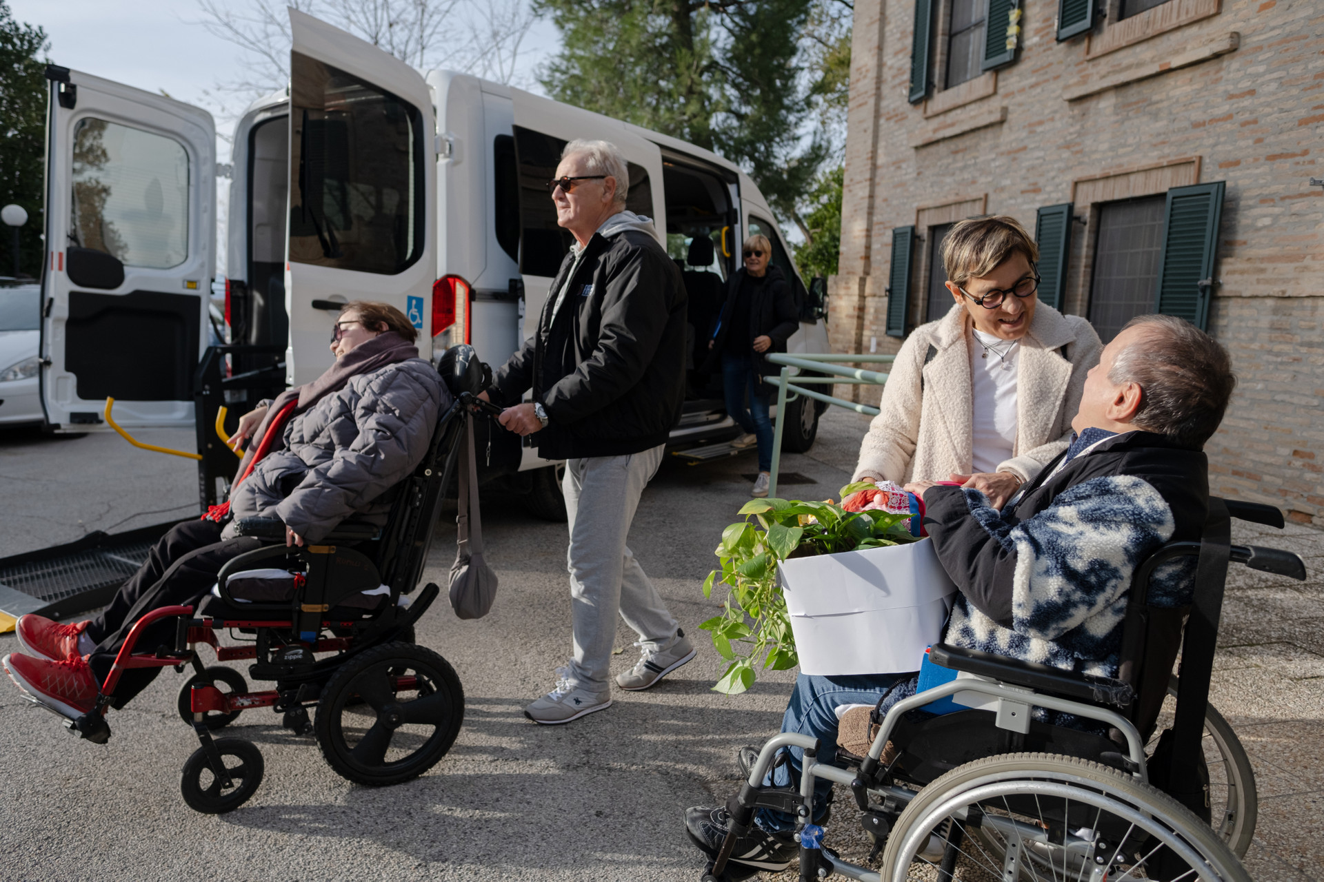 Gli ospiti residenziali della sede di S.Stefano a Osimo hanno preparato le loro valigie e sono pronti per montare sul pulmino che li porterà nella nuova loro casa al Centro Nazionale, due utenti in sedia a rotelle che partono per essere trasferiti
