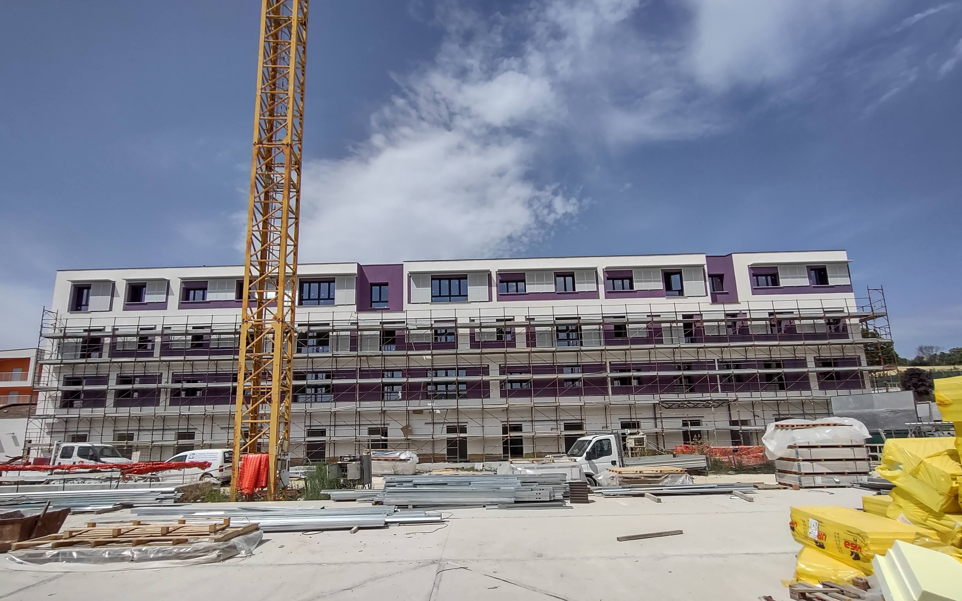 Cantiere del Secondo Lotto del Centro Nazionale di Osimo. Veduta esterna di palazzina con pareti viola in fase di ultimazione. Ancora presente la gru davanti all'edificio.