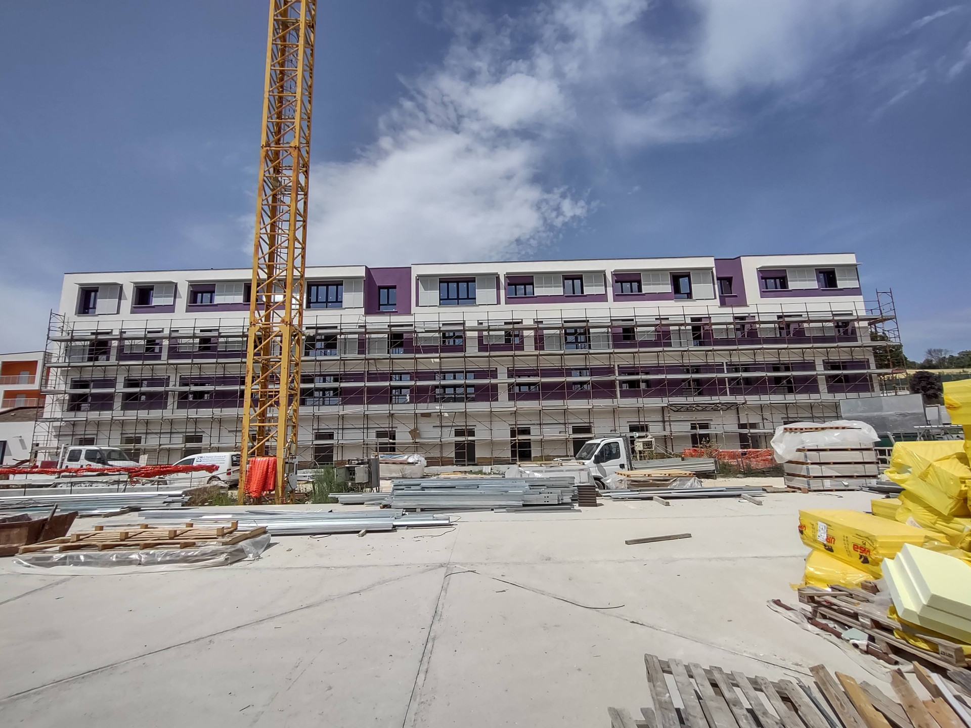 Cantiere del Secondo Lotto del Centro Nazionale di Osimo. Veduta esterna di palazzina con pareti viola in fase di ultimazione. Ancora presente la gru davanti all'edificio.