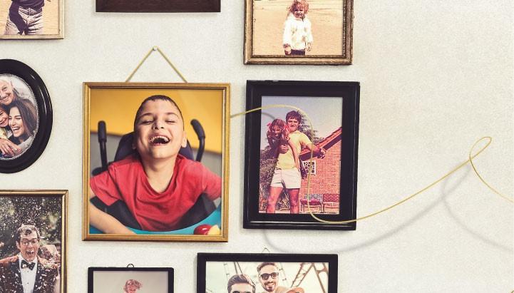 Immagine della campagna Lasciti: una parete con tante foto ricordo incorniciate, tra le quali una raffigura il sorriso di Francesco, uno dei piccoli ospiti della Lega del Filo d'Oro