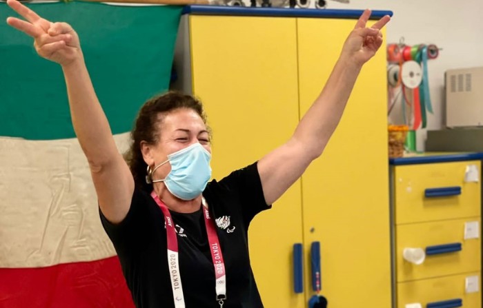 Matilde alza le braccia al cielo nella sede della Lega felice ddei traguardi raggiungi. Alle sue spalle la bandiera italiana