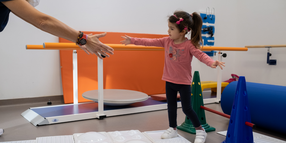 Letizia, bambina con la sindrome di Charge di 10 anni circa, mentre fa esercizi motori con Francesca, la fisioterapista.