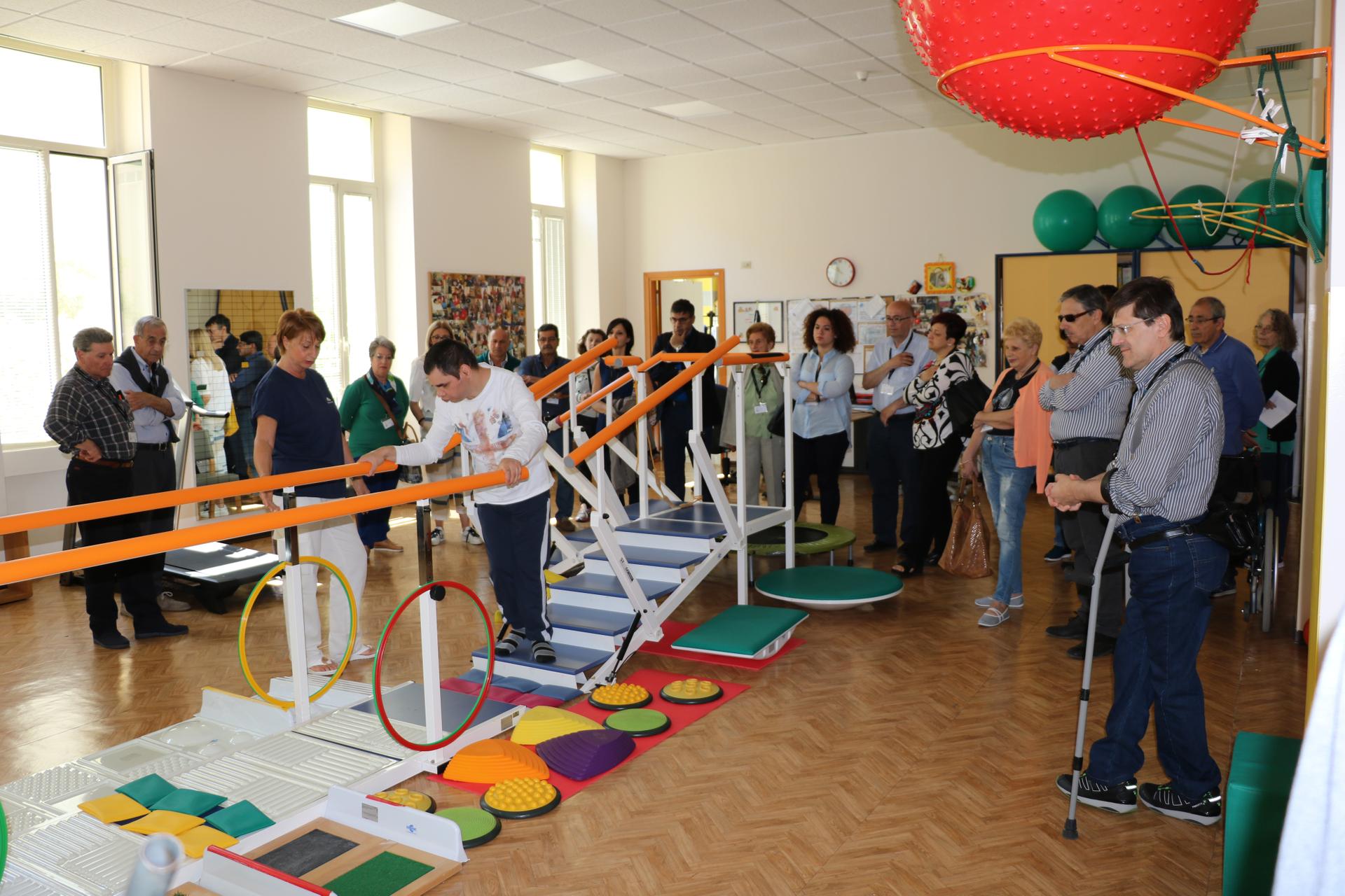 Giornata del Sostenitore - I sostenitori in visita osservanoun giovane utente che svolge attività di fisioterapia nella palestra del Centro