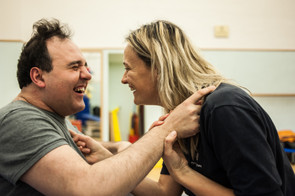 Alberto, utente adulto del Centro di Osimo della Lega del Filo d'Oro, ride divertito insieme alla fisioterapista. Foto di profilo dei due faccia a faccia