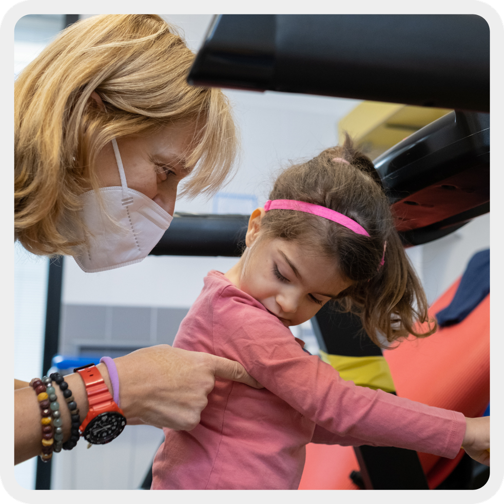 Letizia, una bambina sordocieca, esegue esercizi di fisioterapia per migliorare la postura e imparare a camminare autonomamente, sotto la guida della fisioterapista.